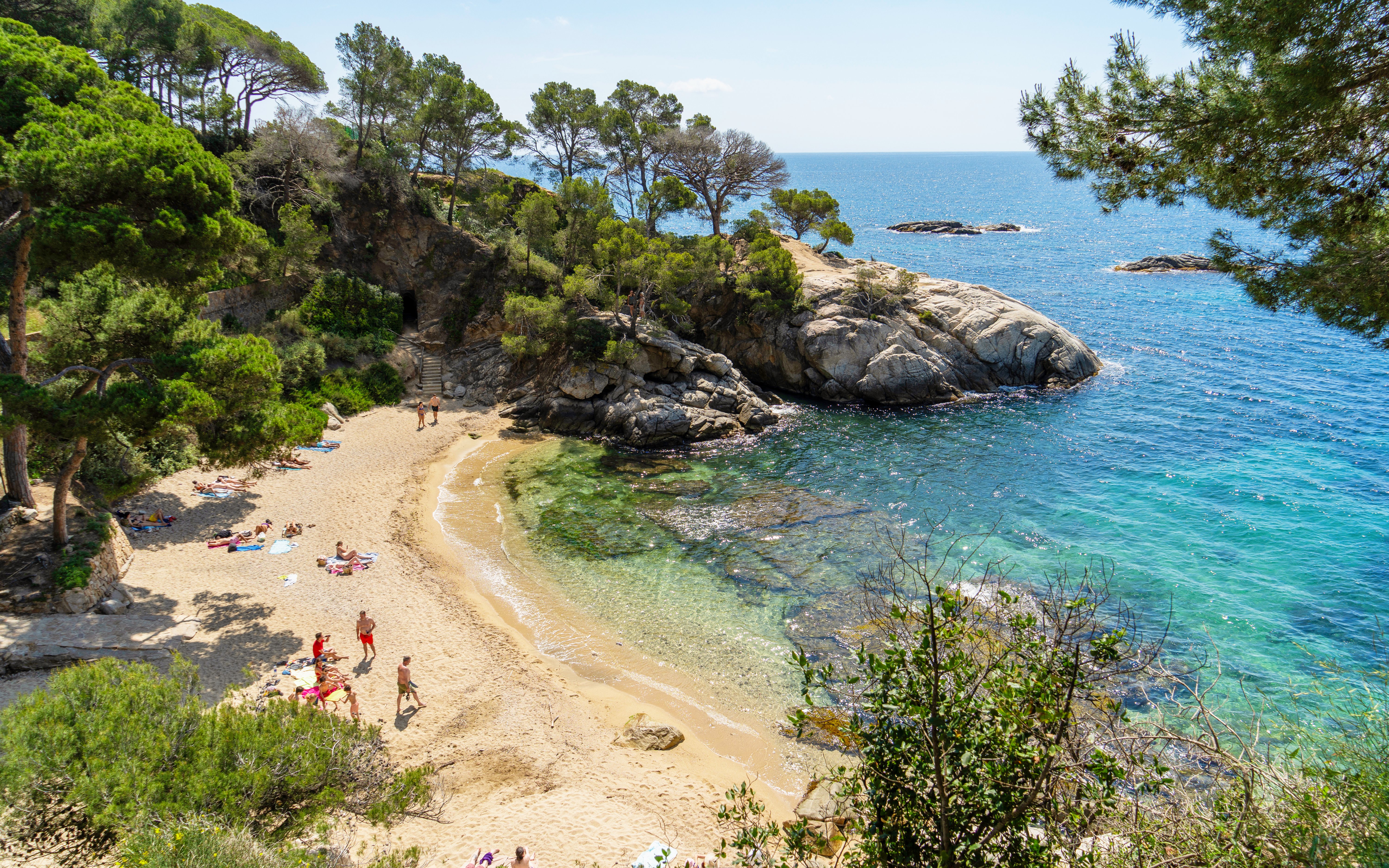 Tourists relaxing on sandy beach at Platja d'Aro, Costa Brava, Spain.
