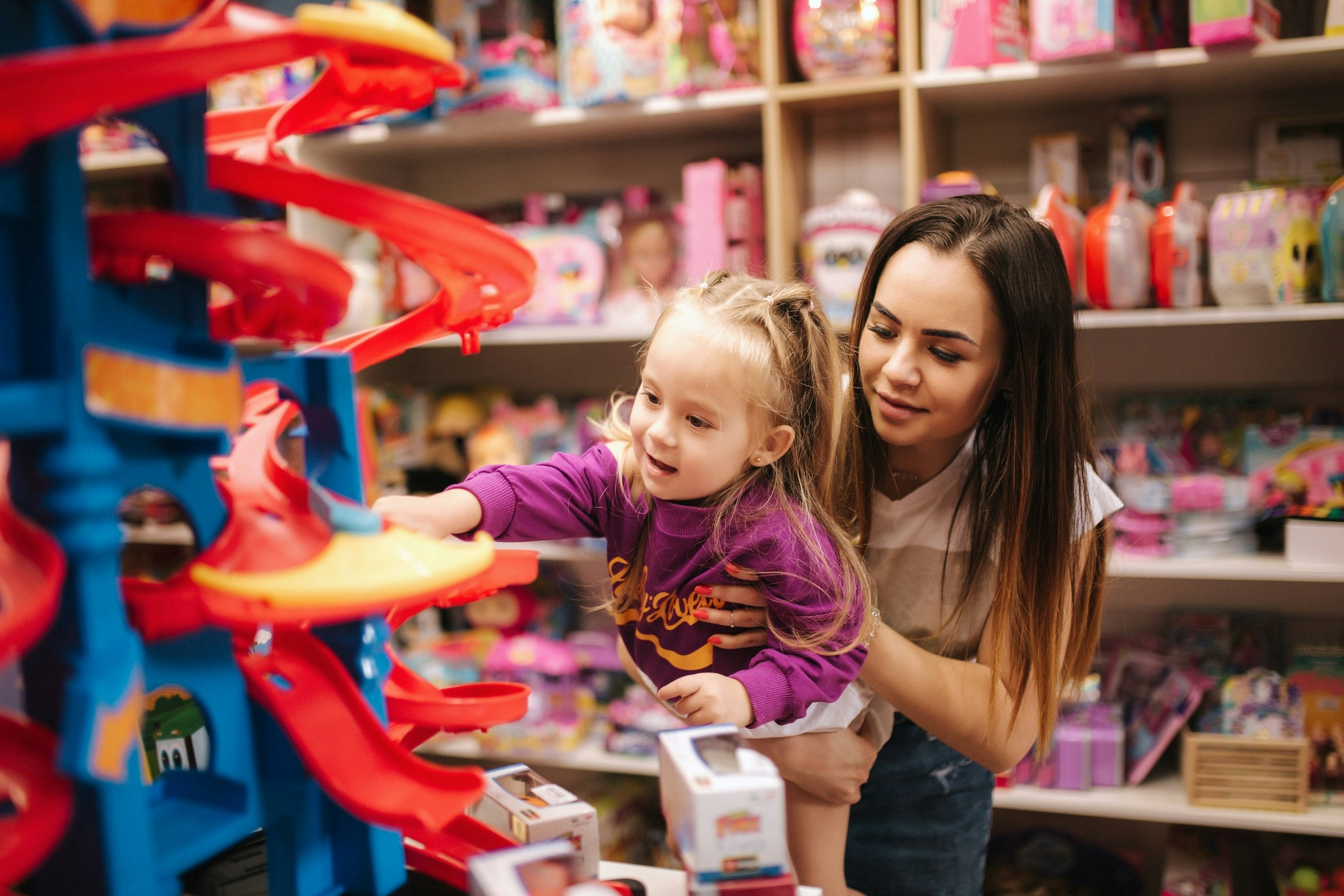 Girl and mother shopping for toys in a store.