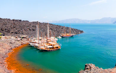 Boats anchored near volcanic rocks at Santorini Volcano Hot Springs, Thirassia.