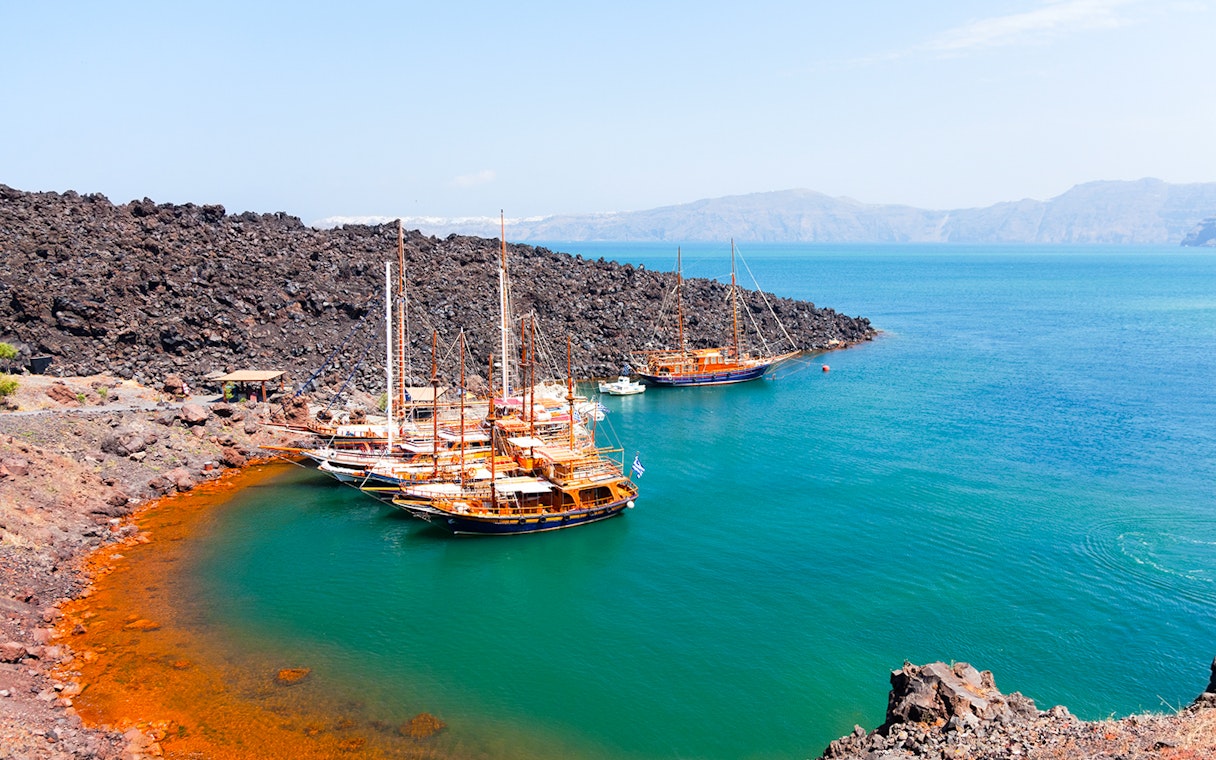 Boats anchored near volcanic rocks at Santorini Volcano Hot Springs, Thirassia.