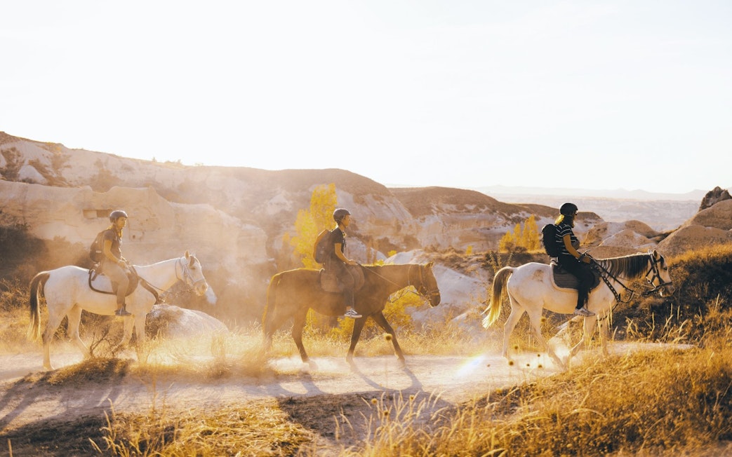 Guests horseback riding through Cappadocia's scenic landscape.