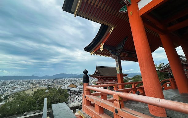 Temple in Kyoto with view of city and mountains in the background.