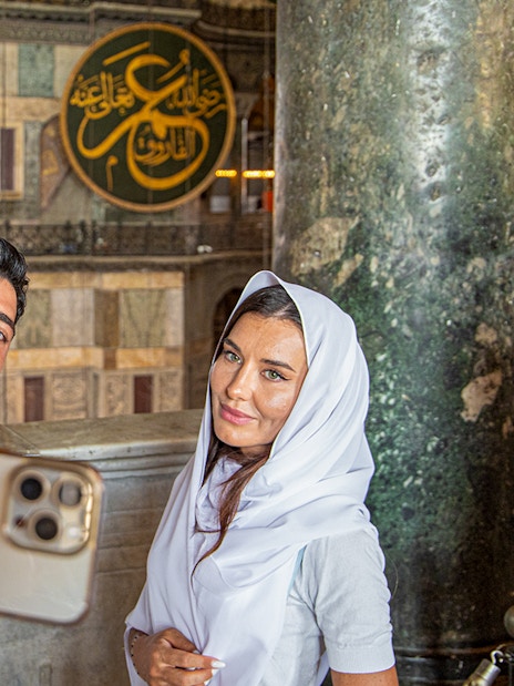 Visitors taking a selfie inside Hagia Sophia, Istanbul, with ornate interior details.