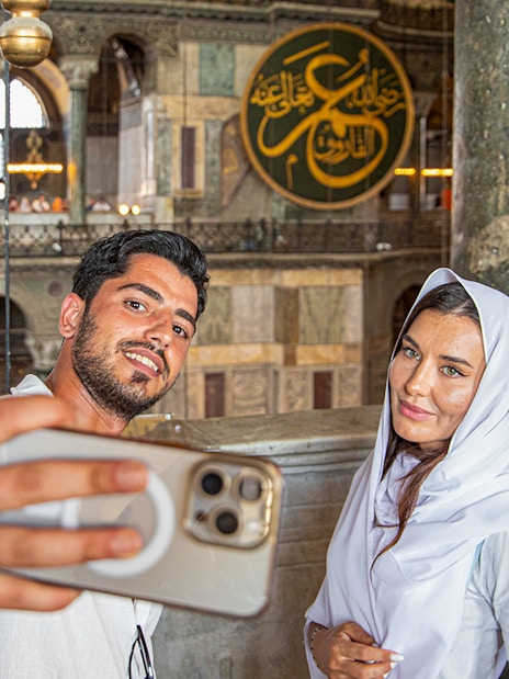 Visitors taking a selfie inside Hagia Sophia, Istanbul, with ornate interior details.
