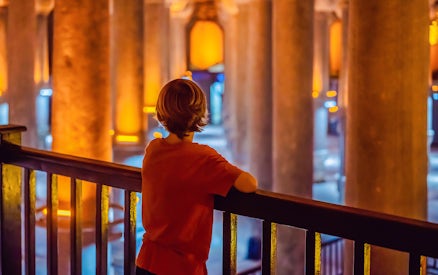 Boy tourist admiring illuminated columns in Istanbul cistern.