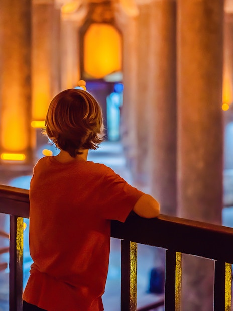 Boy tourist admiring illuminated columns in Istanbul cistern.