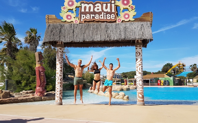 Visitors jumping under tiki arch at Aquopolis Costa Daurada, Tarragona water park.