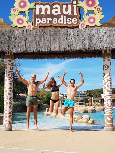 Visitors jumping under tiki arch at Aquopolis Costa Daurada, Tarragona water park.