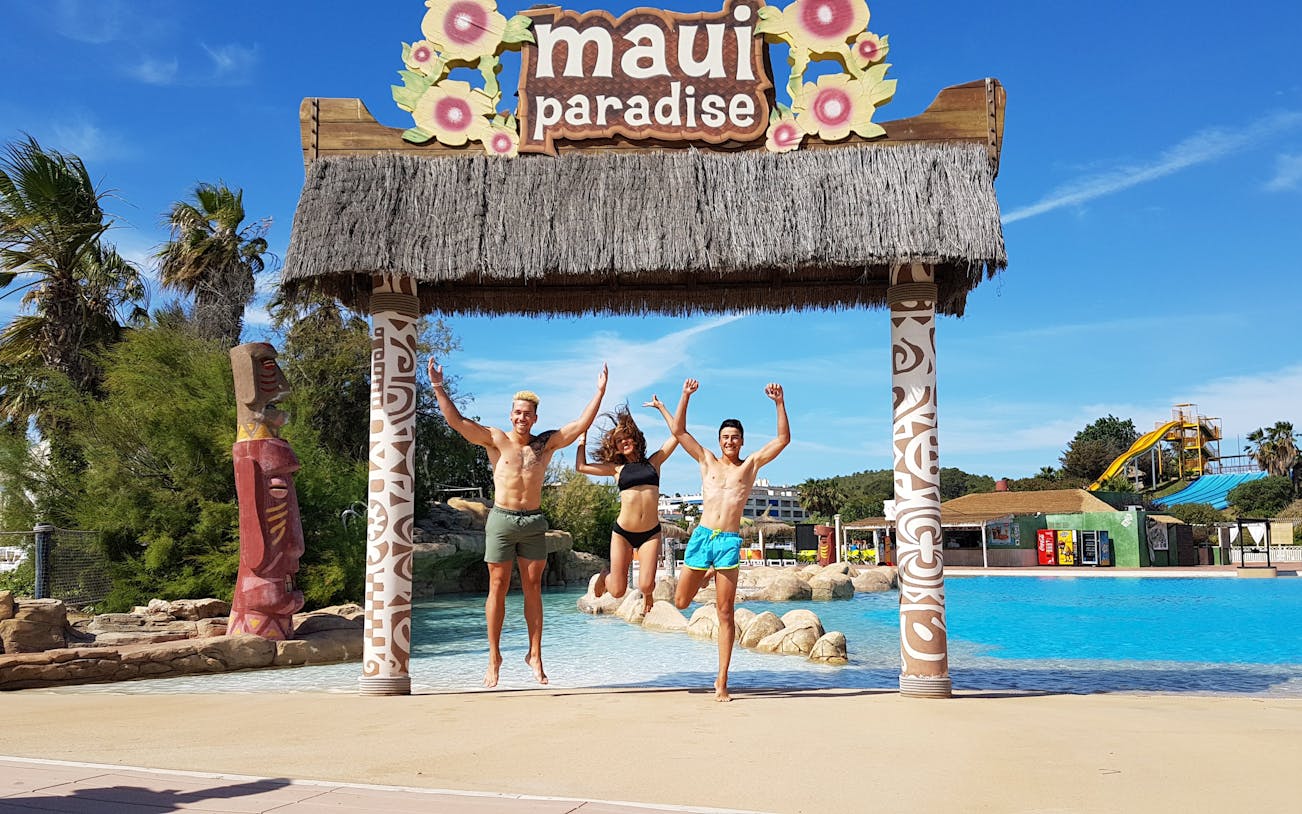 Visitors jumping under tiki arch at Aquopolis Costa Daurada, Tarragona water park.