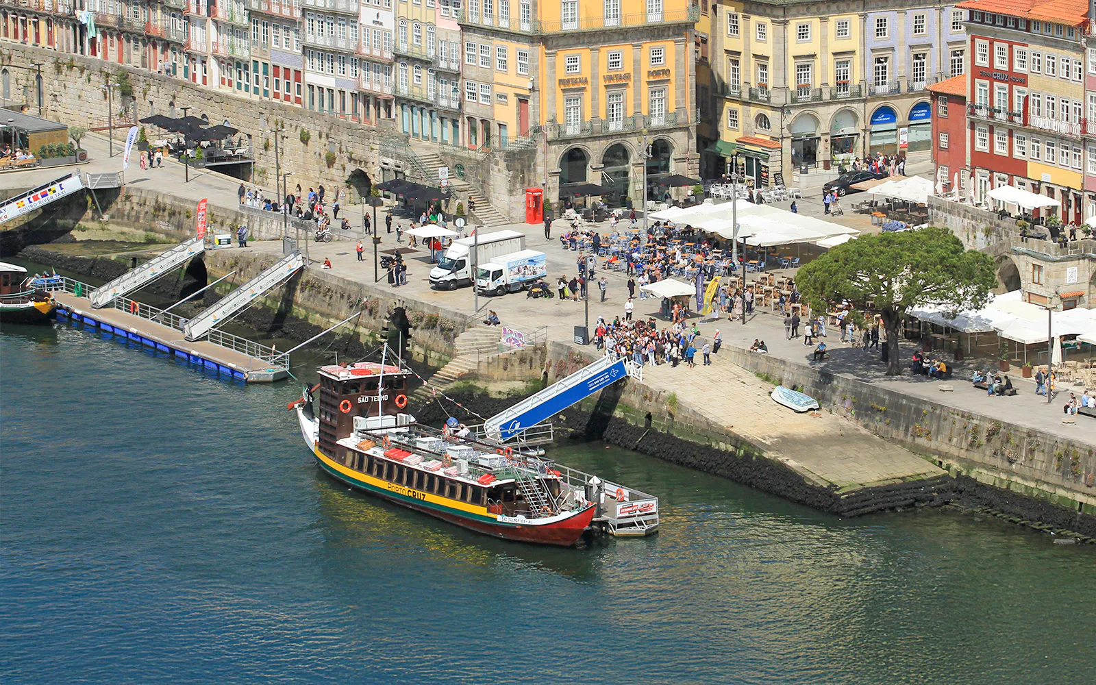 Porto cruise pier with docked tour boat and Ribeira Square in the background.