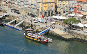 Porto cruise pier with docked tour boat and Ribeira Square in the background.