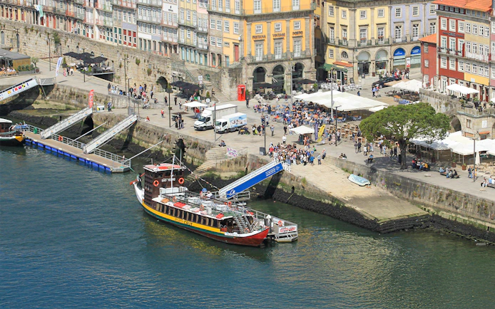 Porto cruise pier with docked tour boat and Ribeira Square in the background.