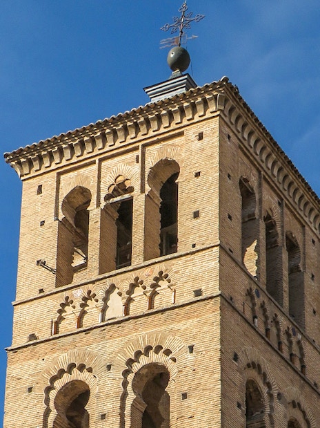 Bell tower of Church of St. Tomé in Toledo against blue sky.
