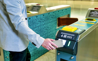 Person scanning phone at Hong Kong Airport Express turnstile.