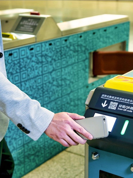 Person scanning phone at Hong Kong Airport Express turnstile.