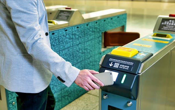 Person scanning phone at Hong Kong Airport Express turnstile.