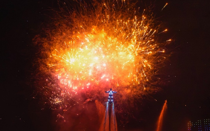 Performer with fireworks at nighttime FiestAventura on the lake, PortAventura, Spain.