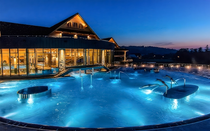 Zakopane Thermal Baths outdoor pool illuminated at night with scenic mountain backdrop.