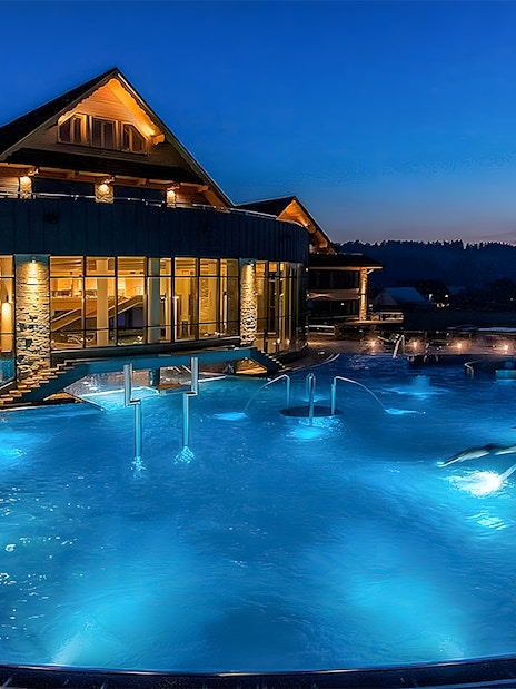 Zakopane Thermal Baths outdoor pool illuminated at night with scenic mountain backdrop.
