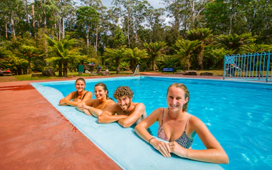 Visitors enjoying a swim at Hastings Caves thermal pool surrounded by lush forest.