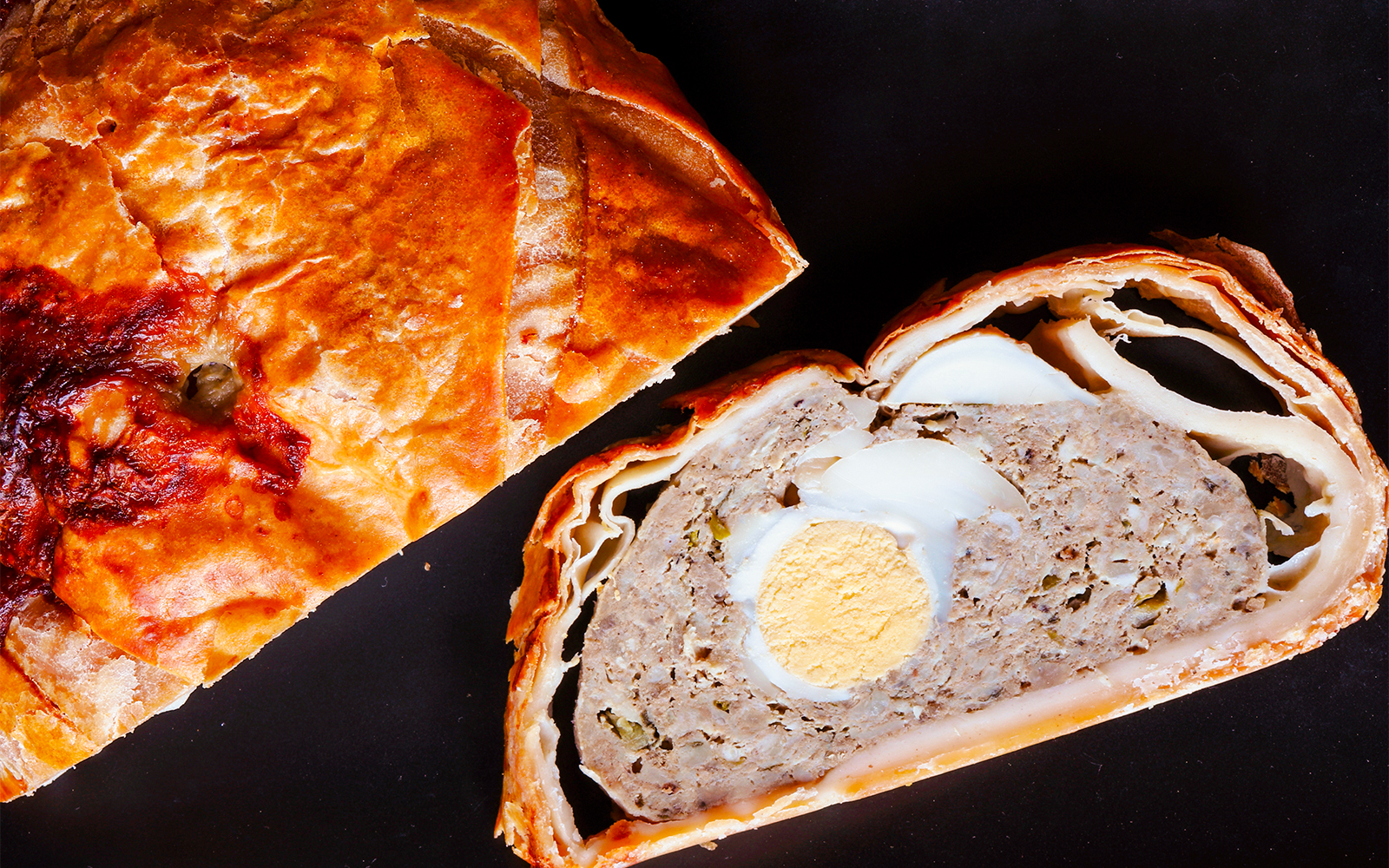 Easter meat pie and slice on slate.
