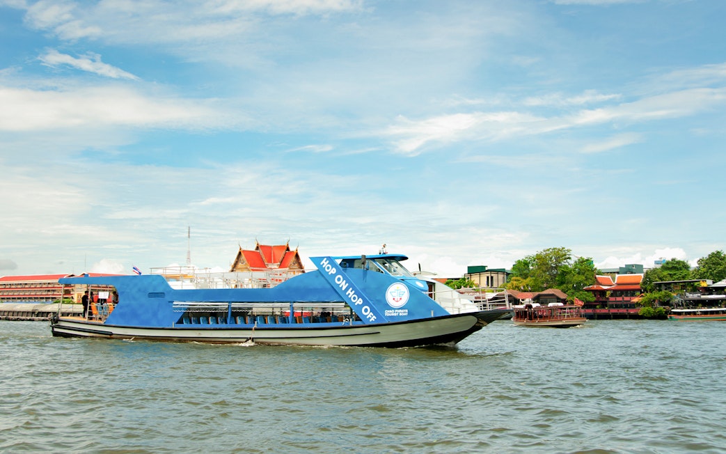 Chao Phraya tourist boat on Bangkok river with temples in the background.