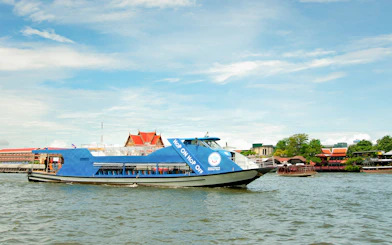 Chao Phraya tourist boat on Bangkok river with temples in the background.