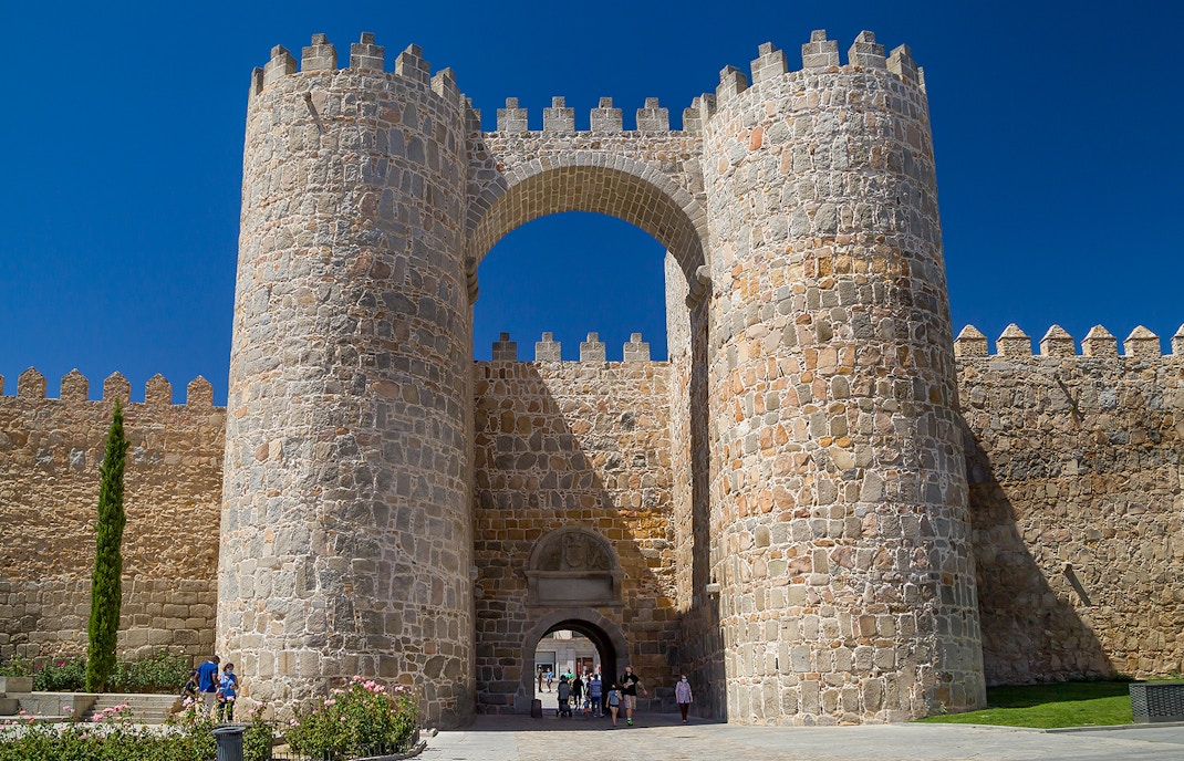 Alcazar gate at Avila Wall, Spain, with tourists walking through.