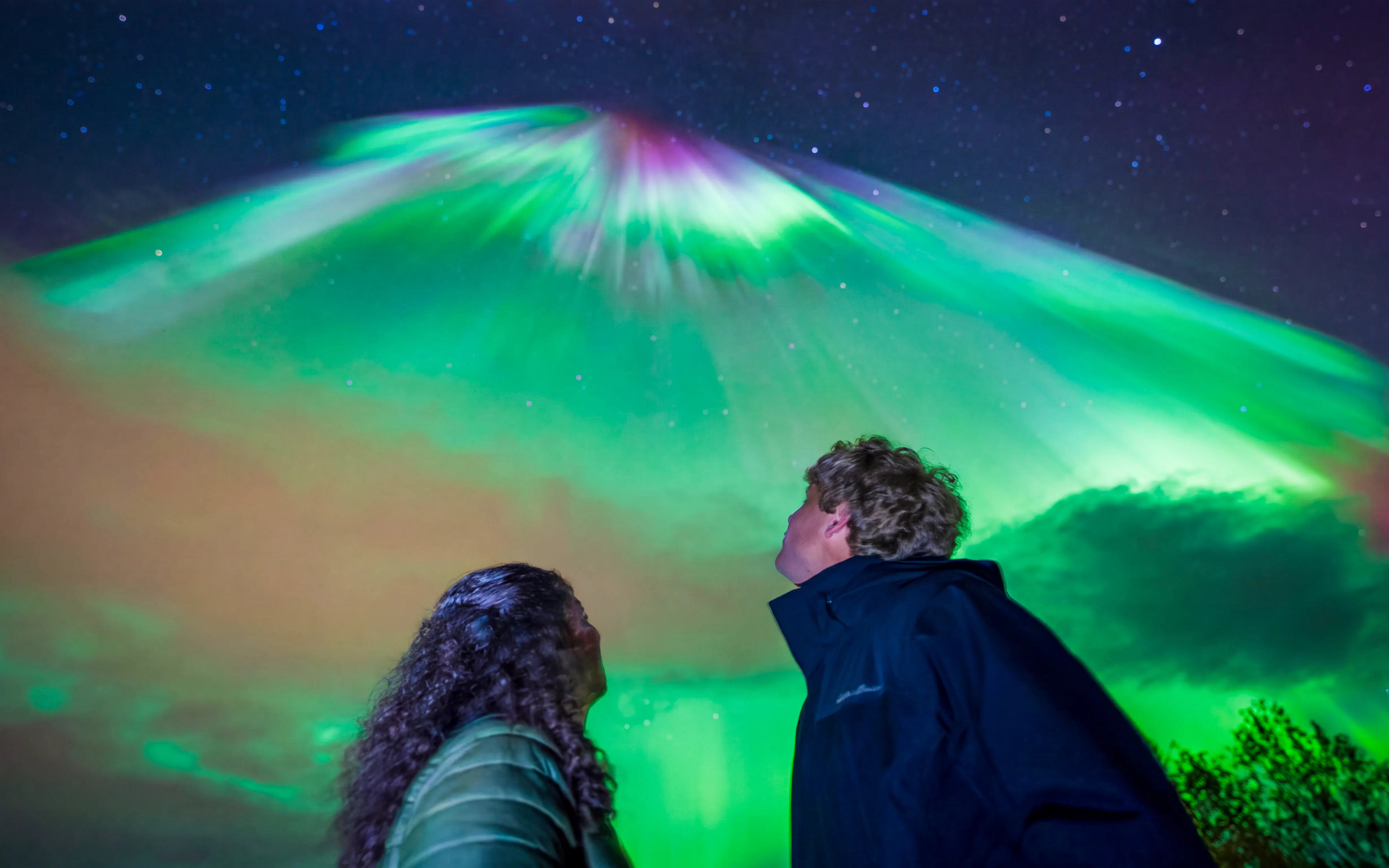 Guests observing vibrant Northern Lights on a photography tour.