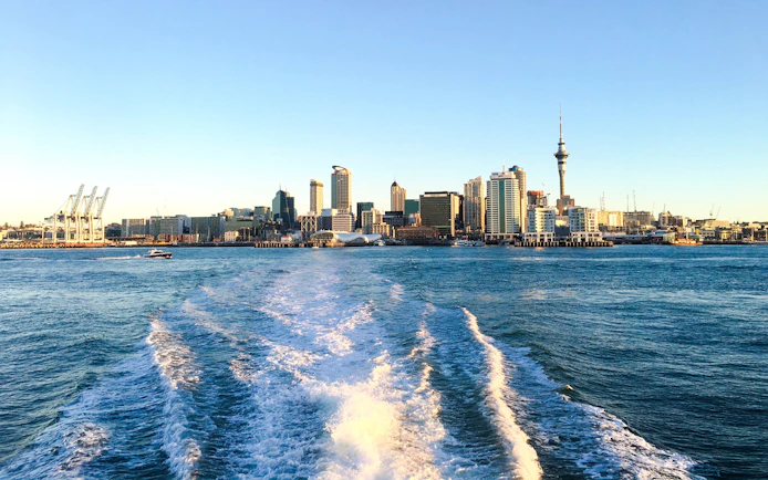 Auckland skyline viewed from the harbor with Sky Tower and city buildings.