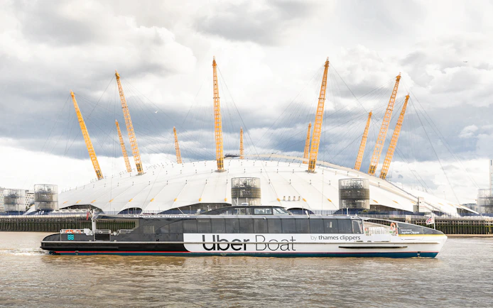 Uber Boat by Thames Clippers passing the O2 Arena on the Thames River.