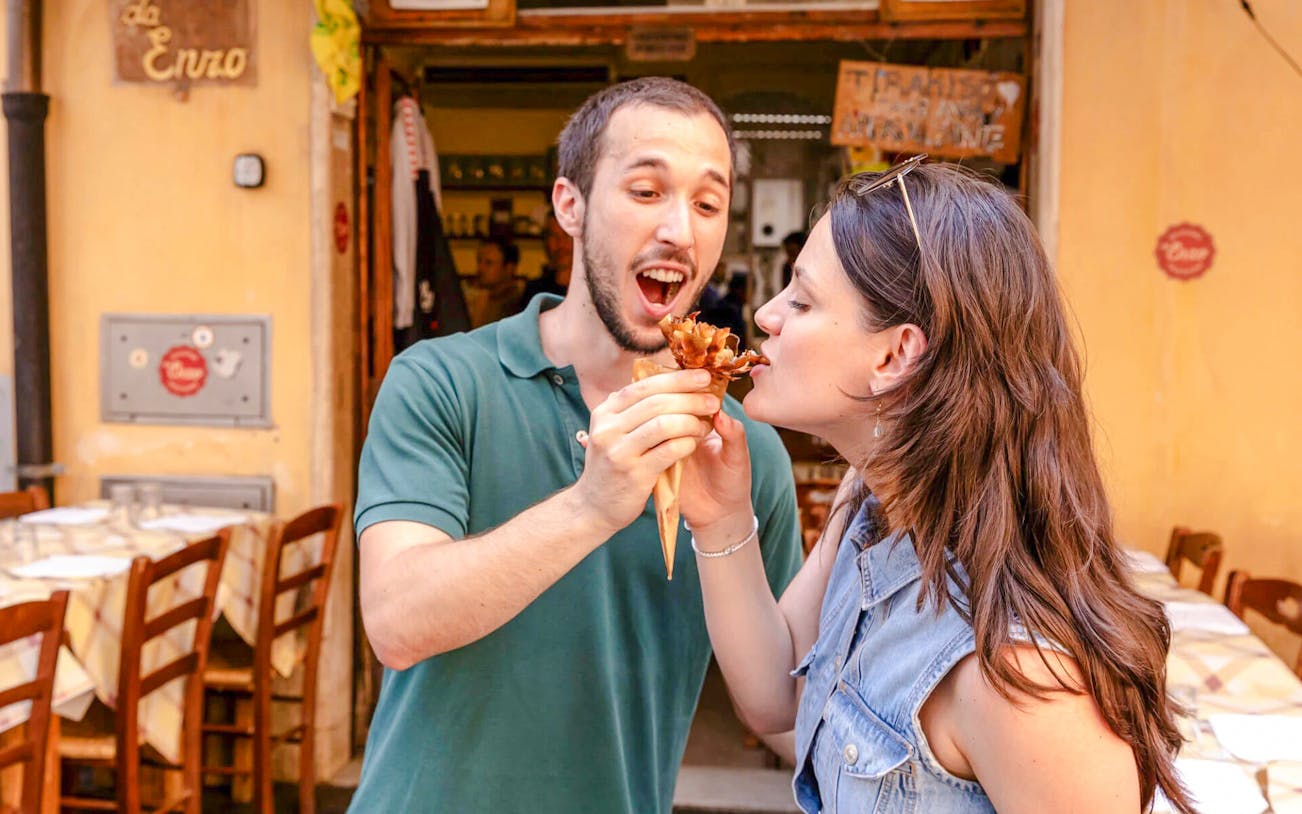 Couple sharing fried artichoke at Da Enzo al 29, Rome food tour.