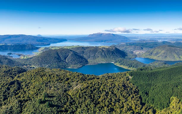 Mount Tarawera aerial view with lush forests and lakes, New Zealand helicopter tour.