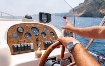 Boat operator steering during Procida Island tour, Italy.
