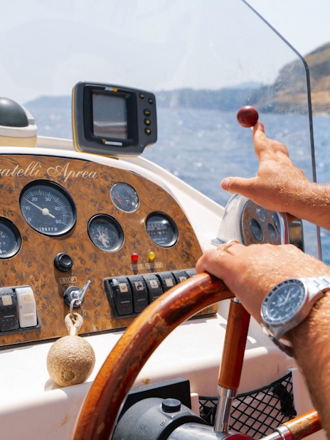 Boat operator steering during Procida Island tour, Italy.