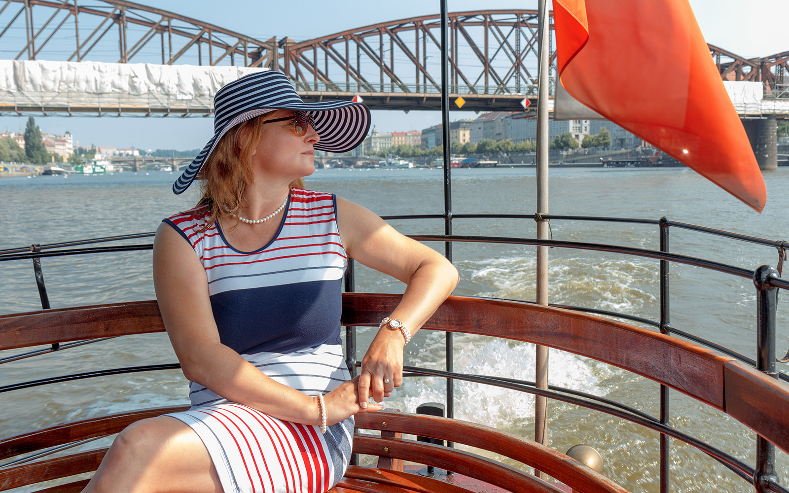 Woman enjoying a cruise on the Vltava River with Prague Castle in the background.