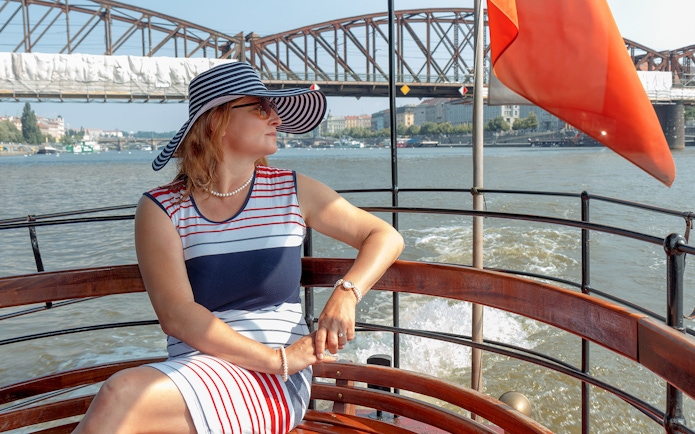 Woman enjoying a cruise on the Vltava River with Prague Castle in the background.