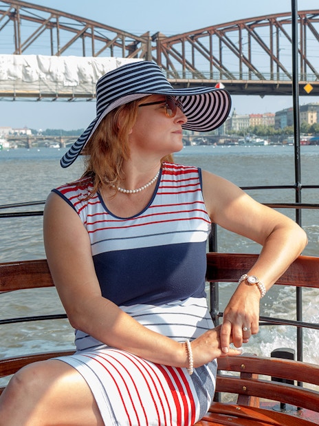 Woman enjoying a cruise on the Vltava River with Prague Castle in the background.