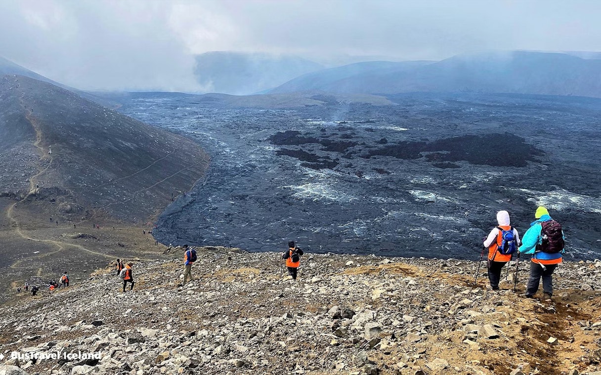 Hikers exploring volcanic terrain in Reykjanes, Iceland, with visible lava fields.