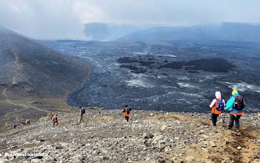 Hikers exploring volcanic terrain in Reykjanes, Iceland, with visible lava fields.