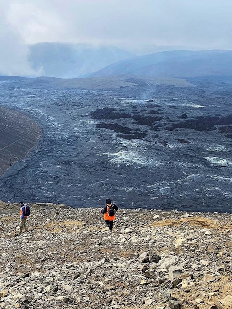 Hikers exploring volcanic terrain in Reykjanes, Iceland, with visible lava fields.