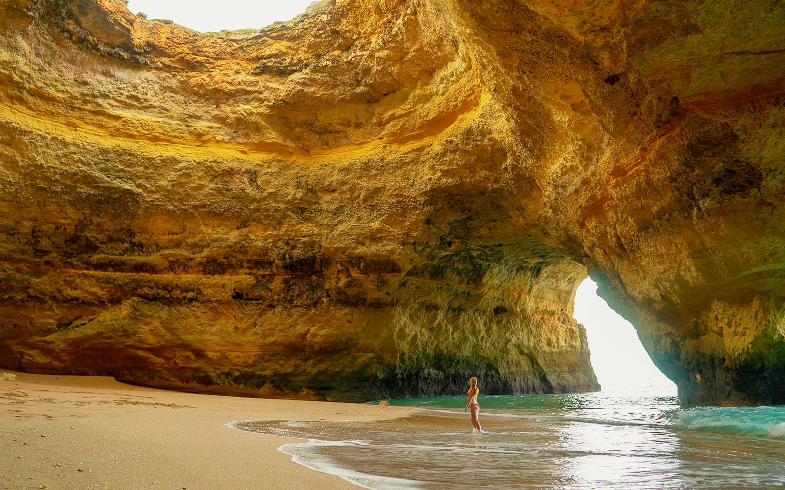 Benagil Beach cave with person standing at the water's edge, Algarve, Portugal.