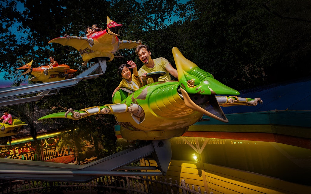 Family on a dinosaur-themed ride at Sunway Lagoon Theme Park.