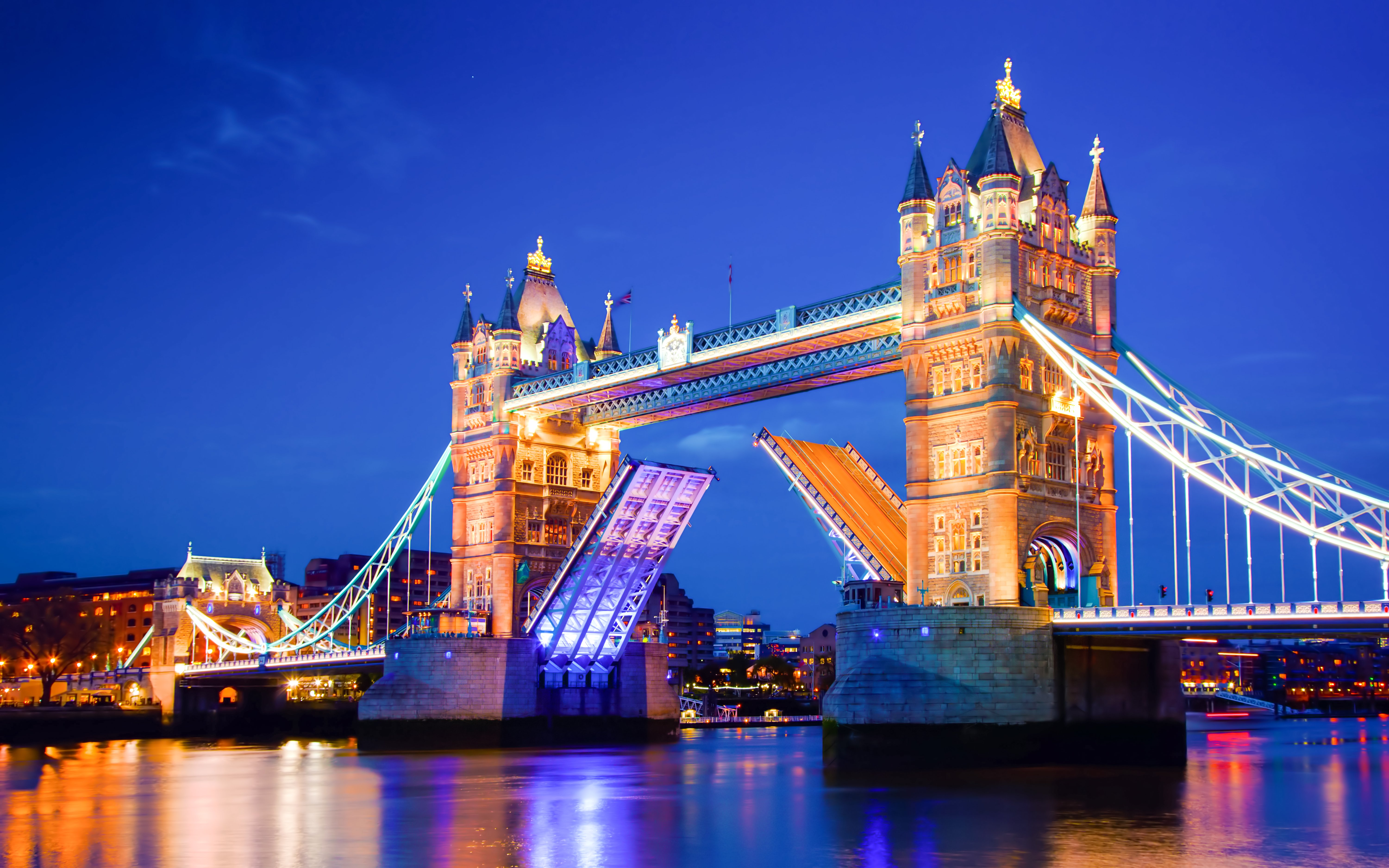 Tower Bridge in London illuminated at night with raised bascules.