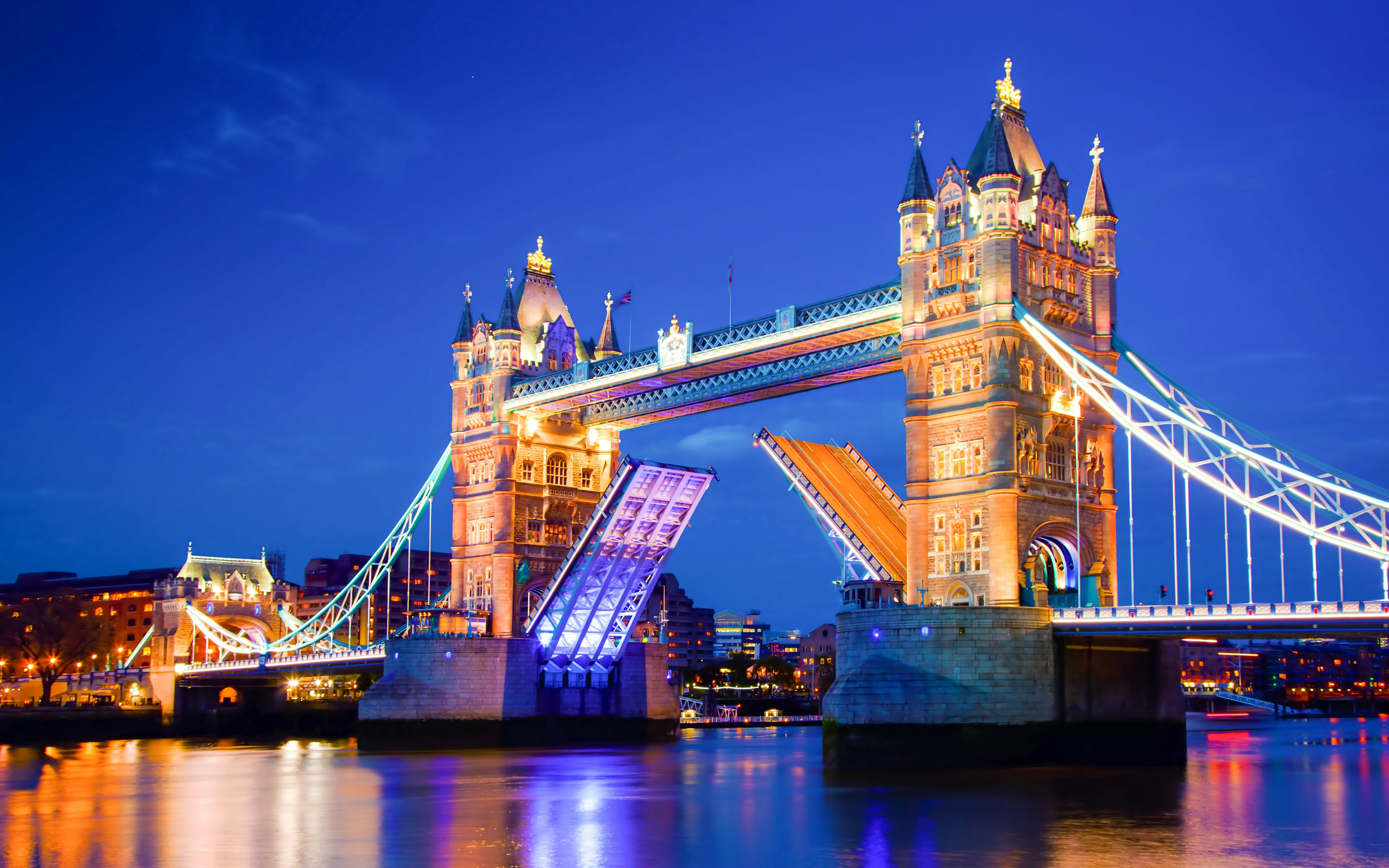 Tower Bridge in London illuminated at night with raised bascules.