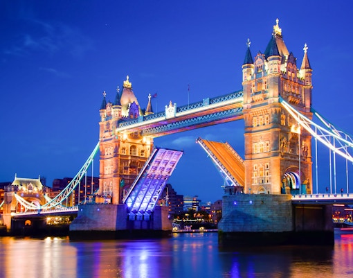 Tower Bridge in London illuminated at night with raised bascules.