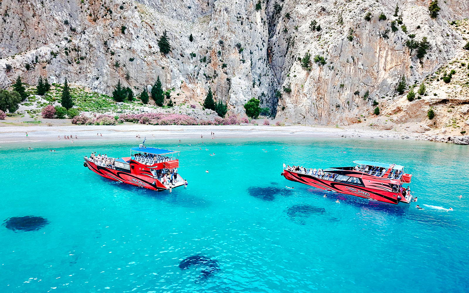 Boats in turquoise waters at St George's Bay, Rhodes, with swimmers nearby.