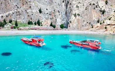 Boats in turquoise waters at St George's Bay, Rhodes, with swimmers nearby.