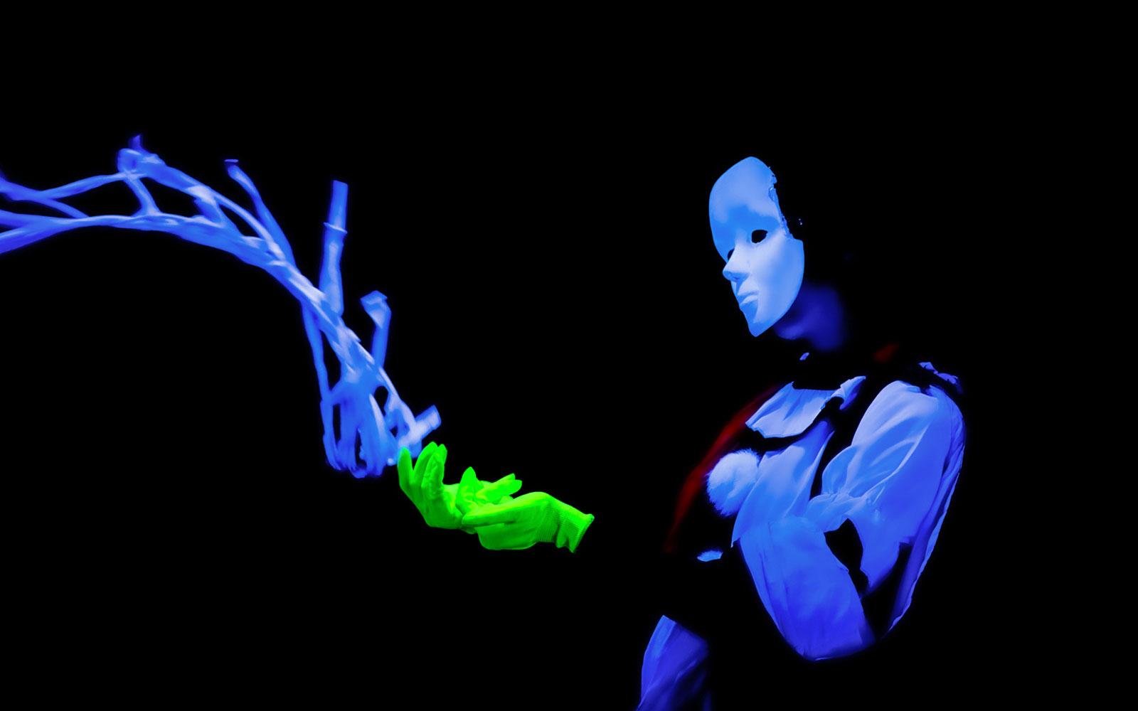Performer in black light theatre, Prague, with glowing mask and gloves.