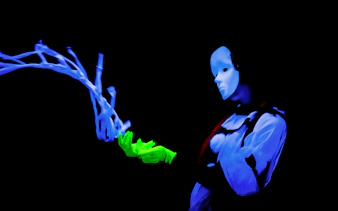 Performer in black light theatre, Prague, with glowing mask and gloves.